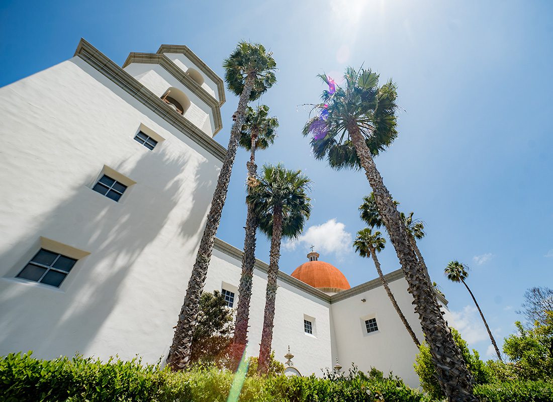 Contact - The Mission Building with Palm Trees Againist a Sunny Clear Blue Sky in San Juan Capistrano California